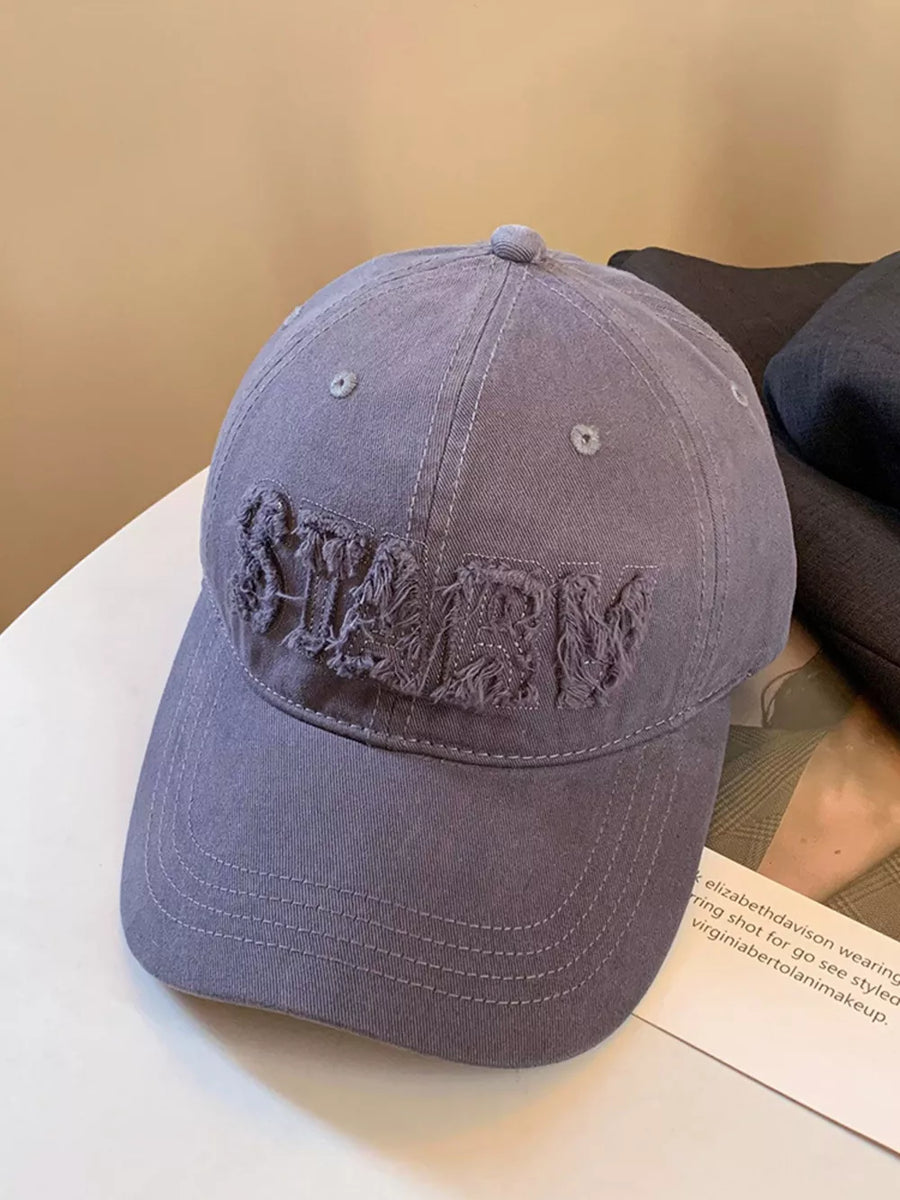 Grey cotton baseball cap with distressed applique letters and frayed details.