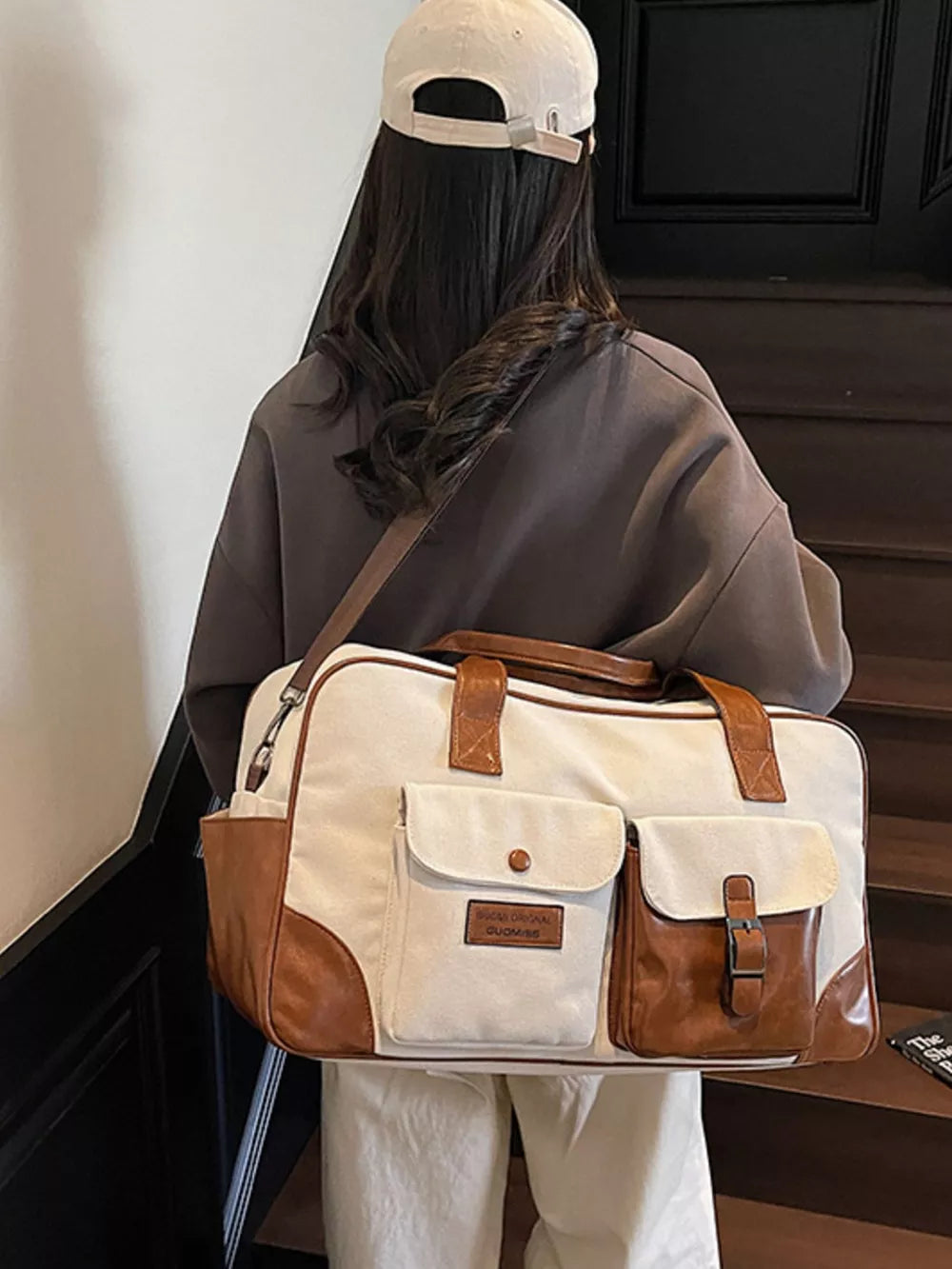 Sophisticated canvas travel bag in cream white with brown leather accents and multiple pockets.