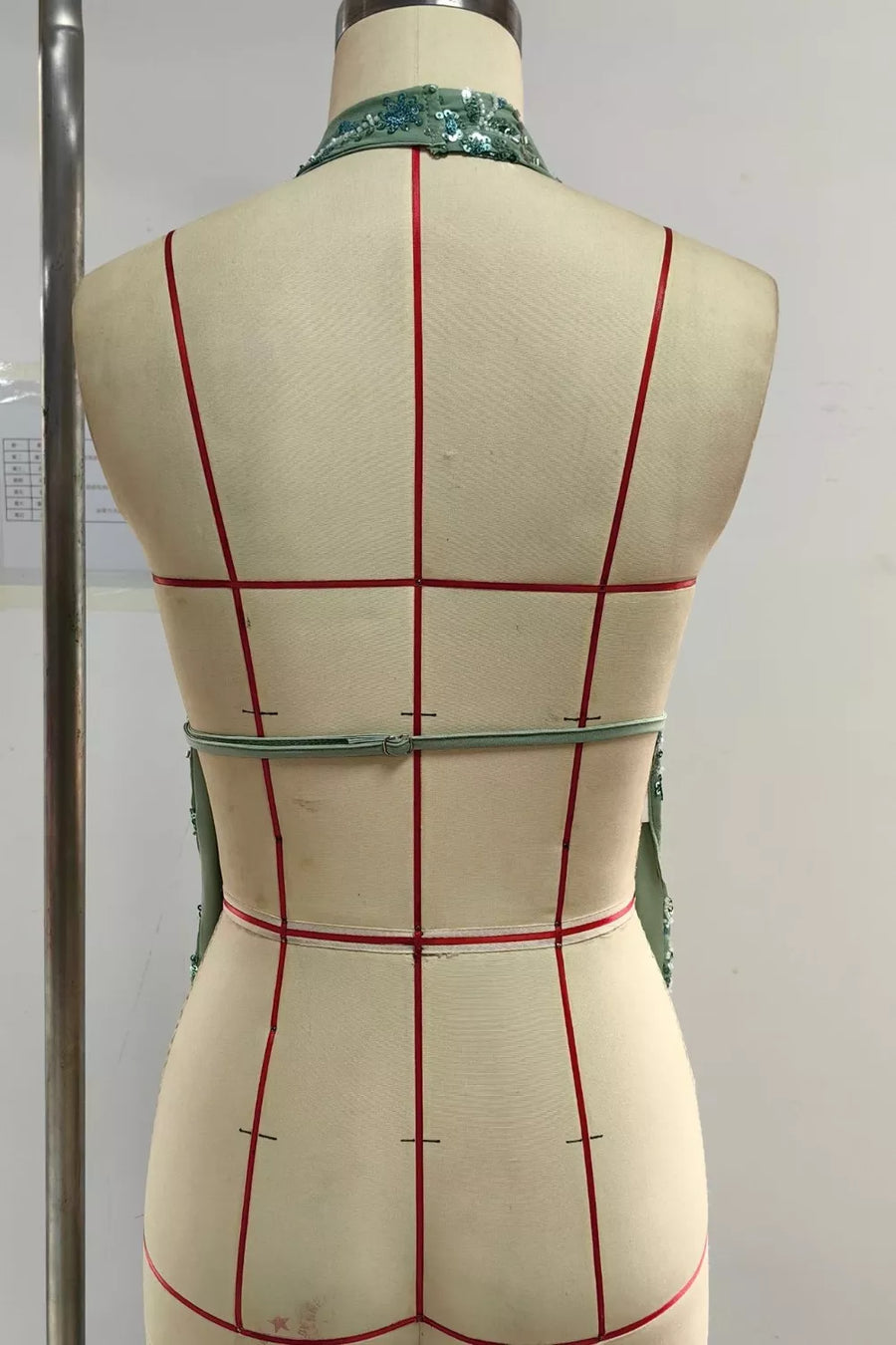 Sequin embellished collar on a light green sleeveless dress with a cinched waist detail.