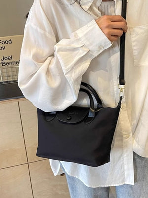 Black nylon mini crossbody bag with flap and top handles.