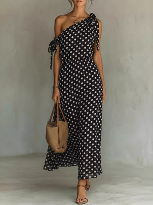 Black polka dot one-shoulder maxi dress with tie details and a flowing skirt.