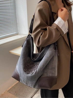 Medium grey canvas tote bag with brown leather trim and embroidered detail.