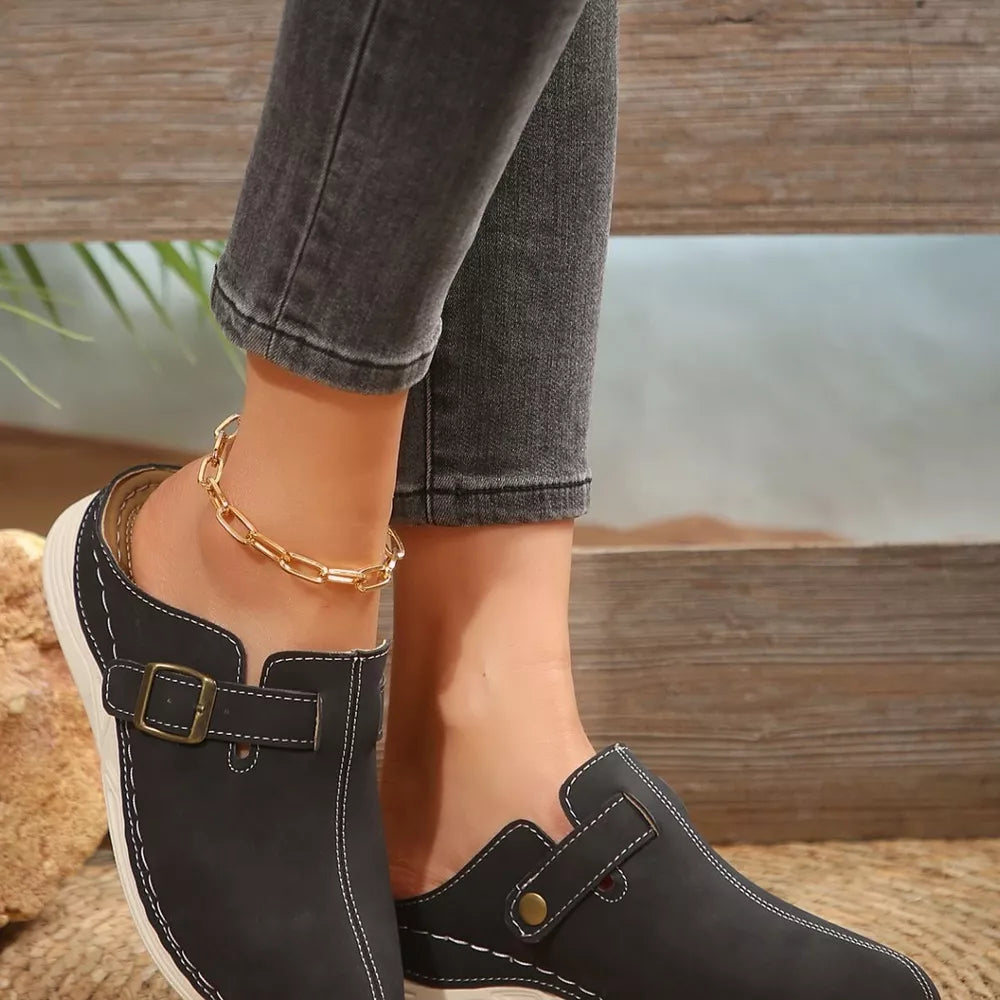 Black slip-on flats with buckle detail and contrast stitching.