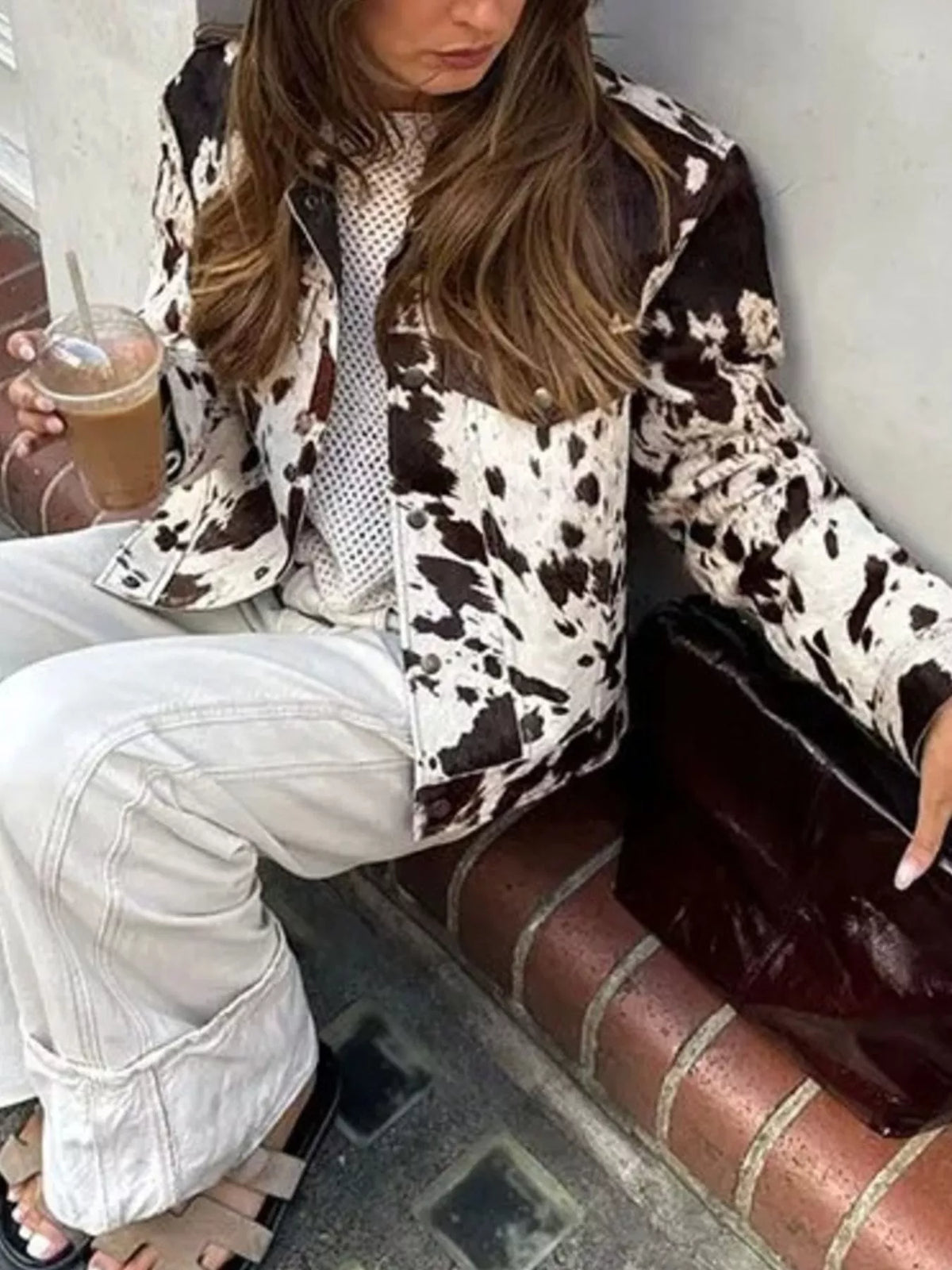 Buttoned collared jacket in cow print with button front closure.