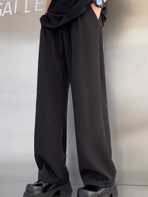 Men's black pleated casual pants with a wide leg and relaxed fit.