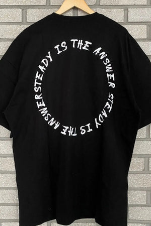 Black oversized t-shirt with white circle text graphic saying "UNSTEADY IS THE ANSWER STEADY IS THE ANSWER