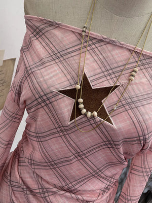 Pink plaid maternity top with asymmetrical ruffle hem and star cutout detail.