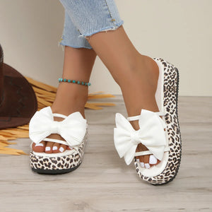 Leopard print platform slides with white bow detail and white straps.