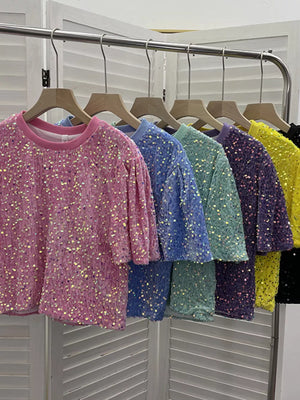 Crew neck t-shirts in pink, blue, green, purple, yellow, and black, all with iridescent sequin embellishments.