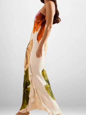 Elegant floral one-shoulder maxi dress in cream with orange and green botanical print and ruffled hem.
