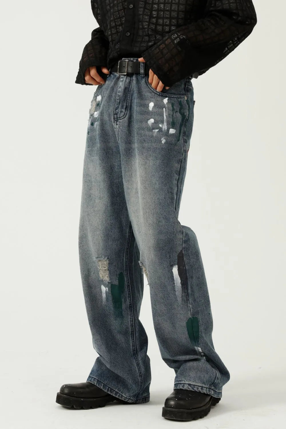Medium wash baggy jeans with white and green paint splatters and distressed details.