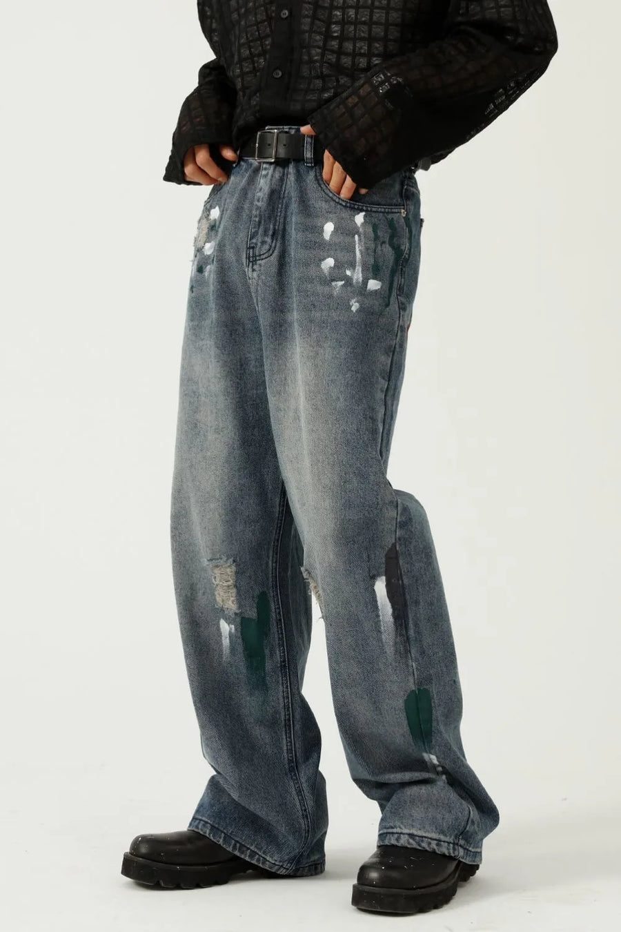 Medium wash baggy jeans with white and green paint splatters and distressed details.