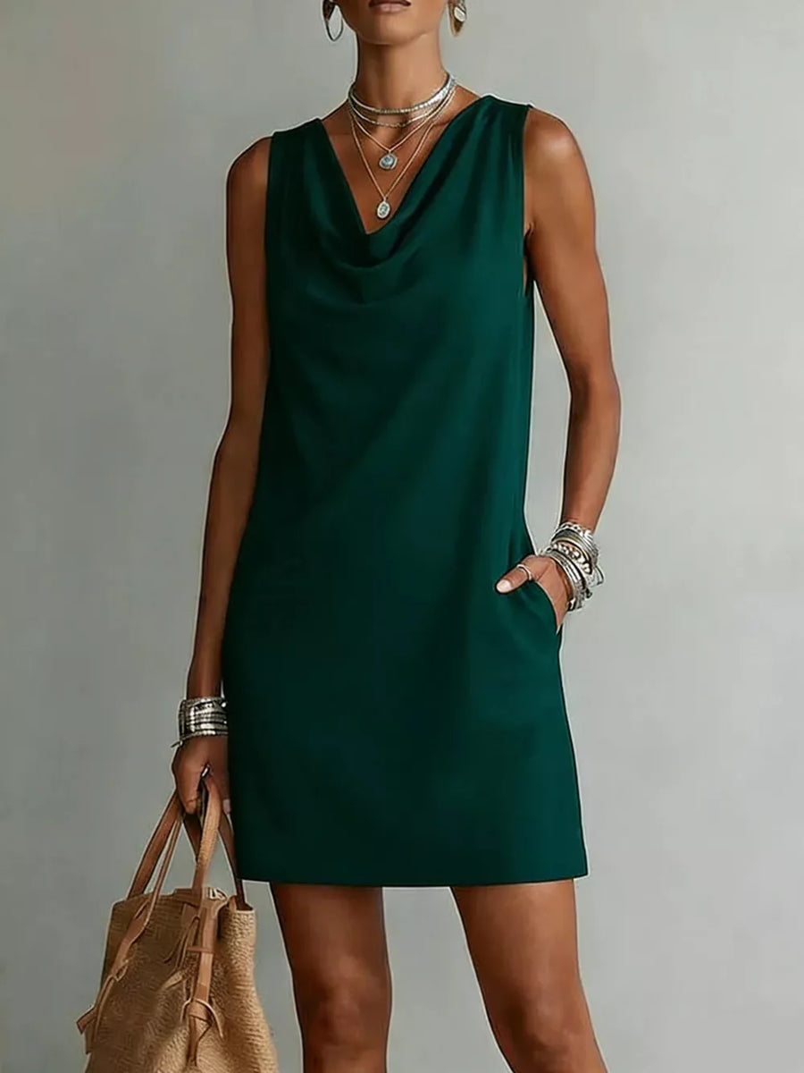 Sleeveless green cowl neck mini dress with pockets, styled with layered necklaces and bracelets.