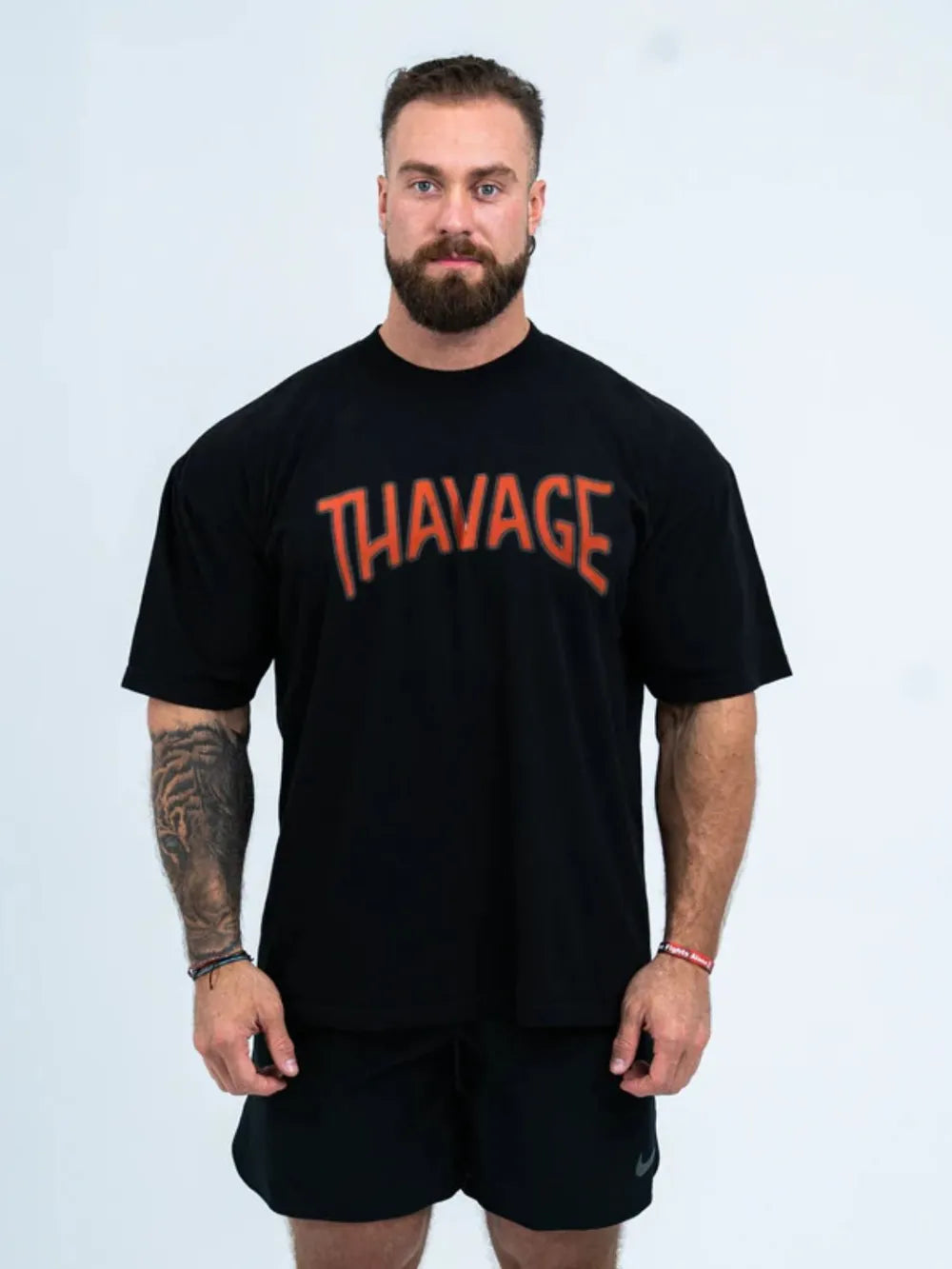 Black oversized graphic tee with orange "THAVAGE" print, short sleeves, crew neck.