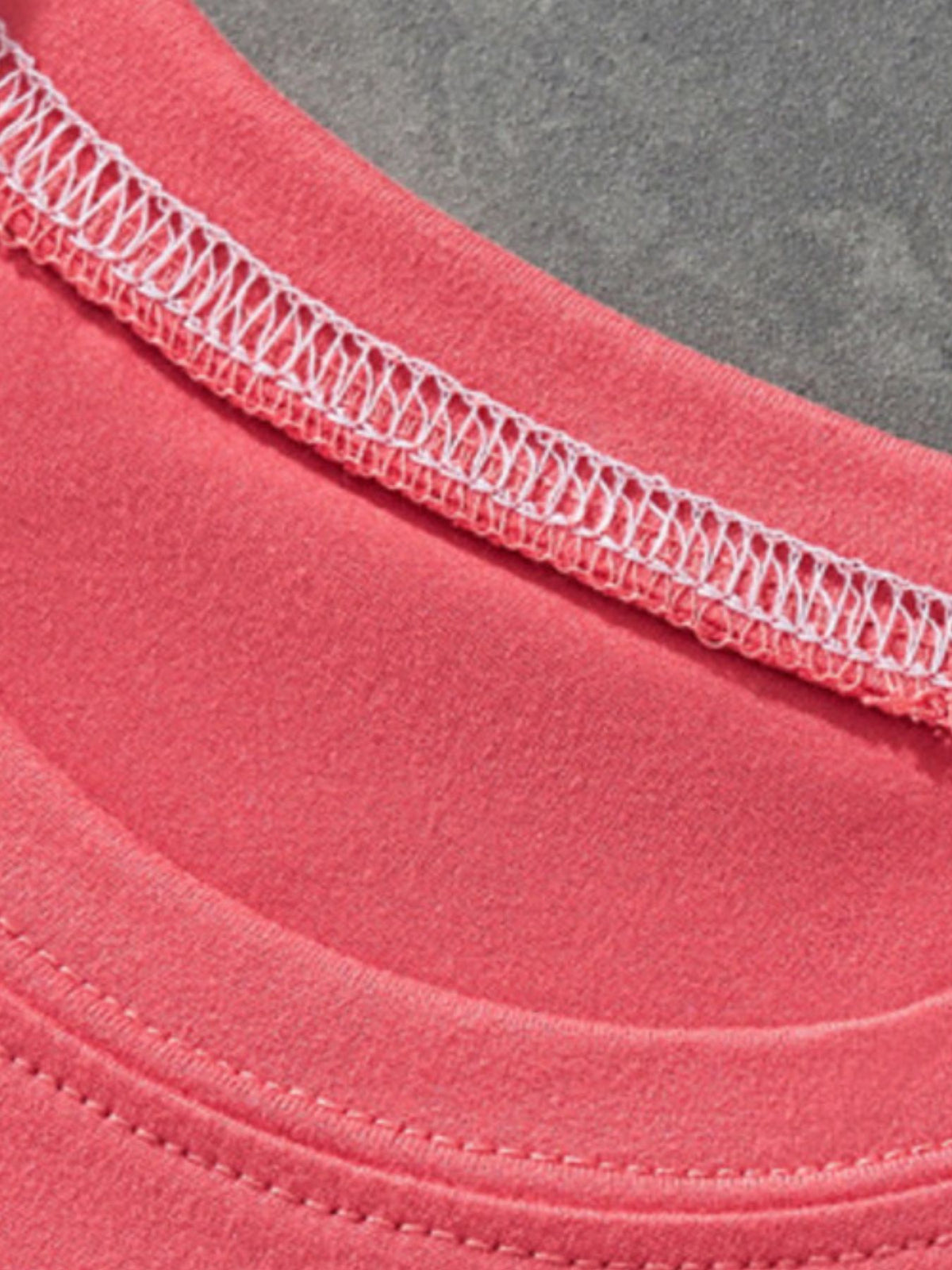 Coral t-shirt with white decorative stitching on the neckline and hem.