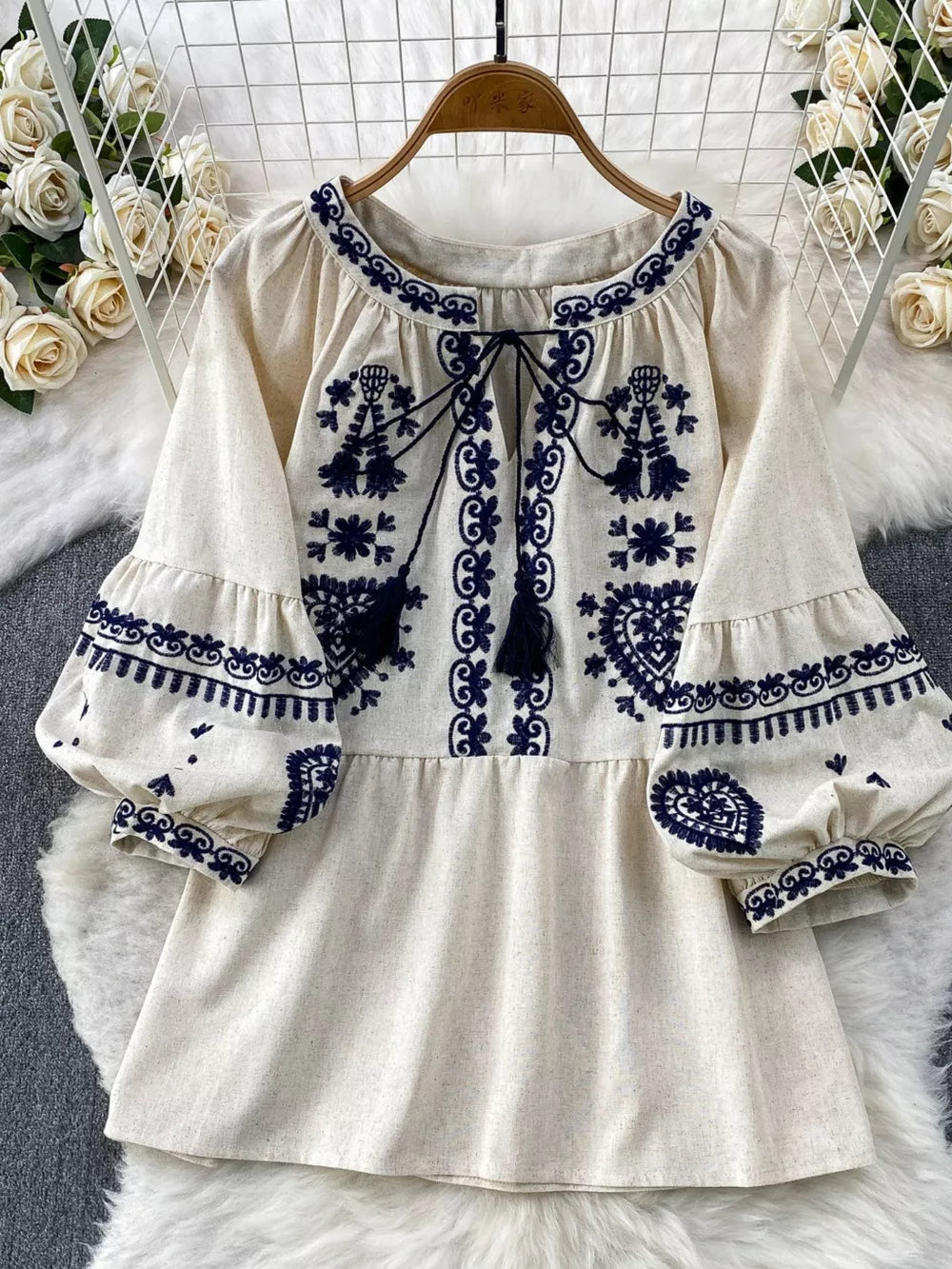Cream tie-neck blouse with intricate blue embroidery and balloon sleeves