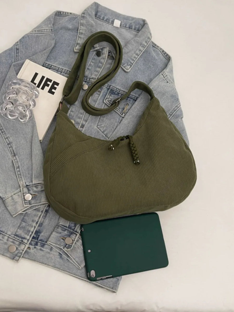 Moss corduroy crescent shoulder bag with braided tassel detail and adjustable strap.