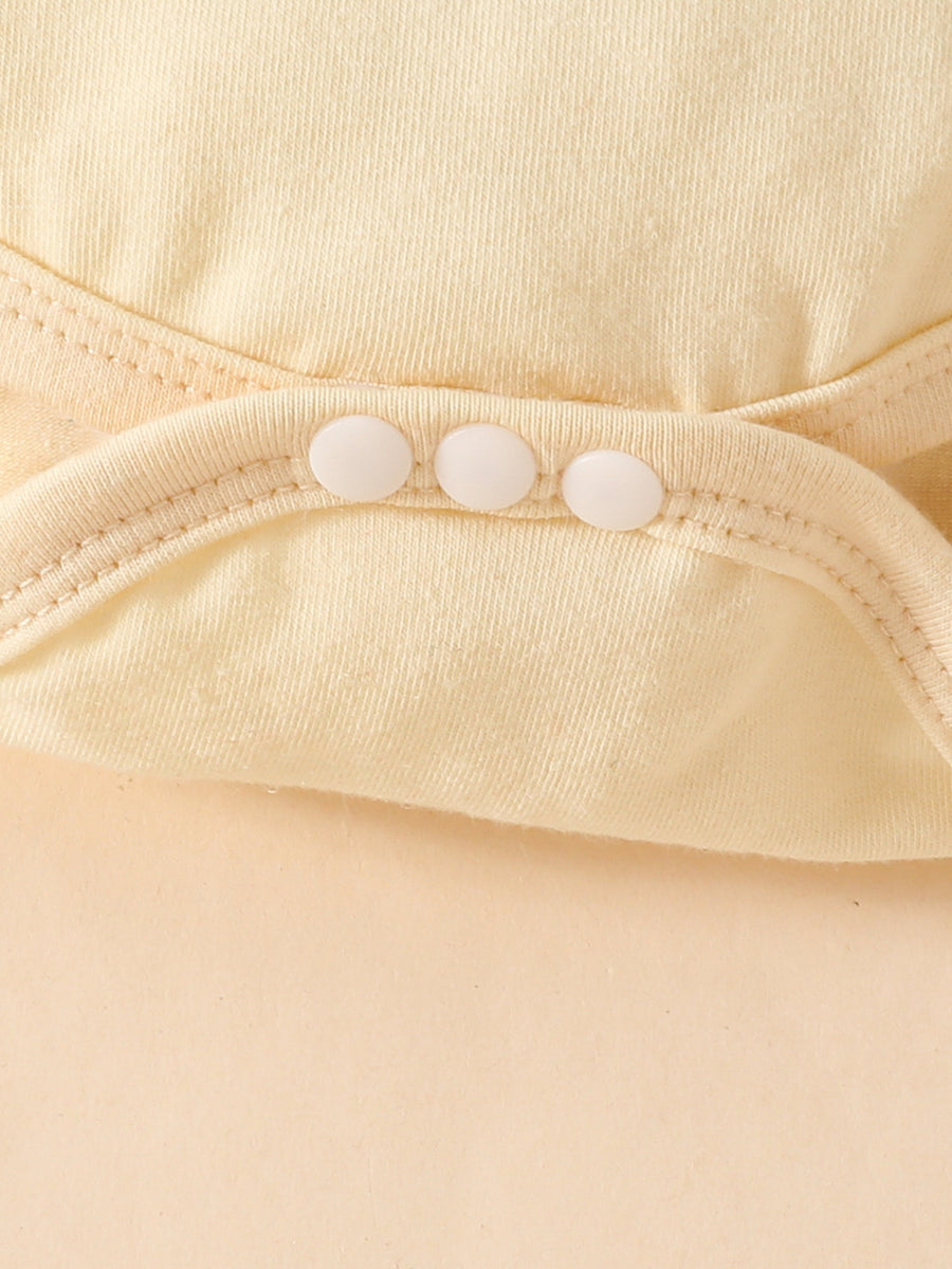Yellow baby bodysuit detail with three white snaps