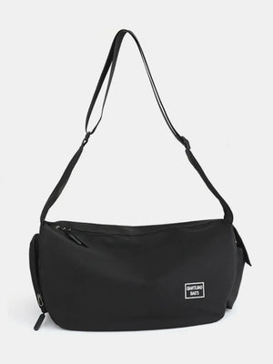Black slouchy crescent crossbody bag with adjustable strap and white logo patch.