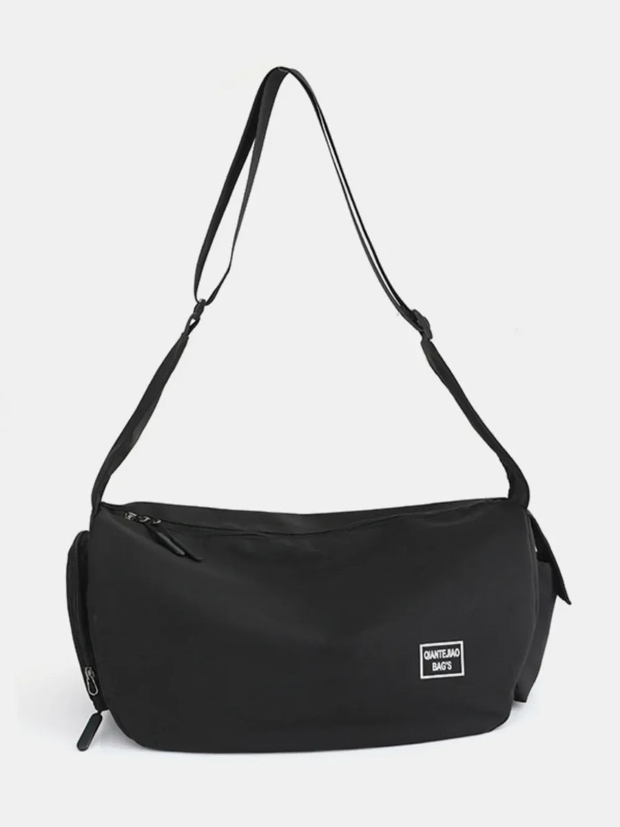 Black slouchy crescent crossbody bag with adjustable strap and white logo patch.