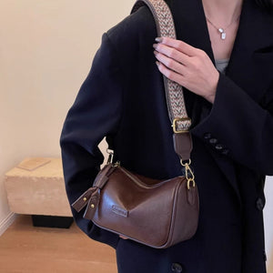 Brown textured PU leather crossbody bag with tassel detail and woven strap.