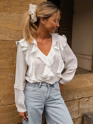 White lace ruffle v-neck blouse with lace trim and long sleeves.