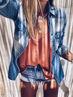 Faded denim shirt with chest pockets and button-down front, styled open over a coral camisole.