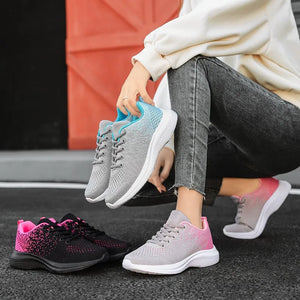 Breathable knit athletic trainers in light gray with blue accents and pink gradient detail.