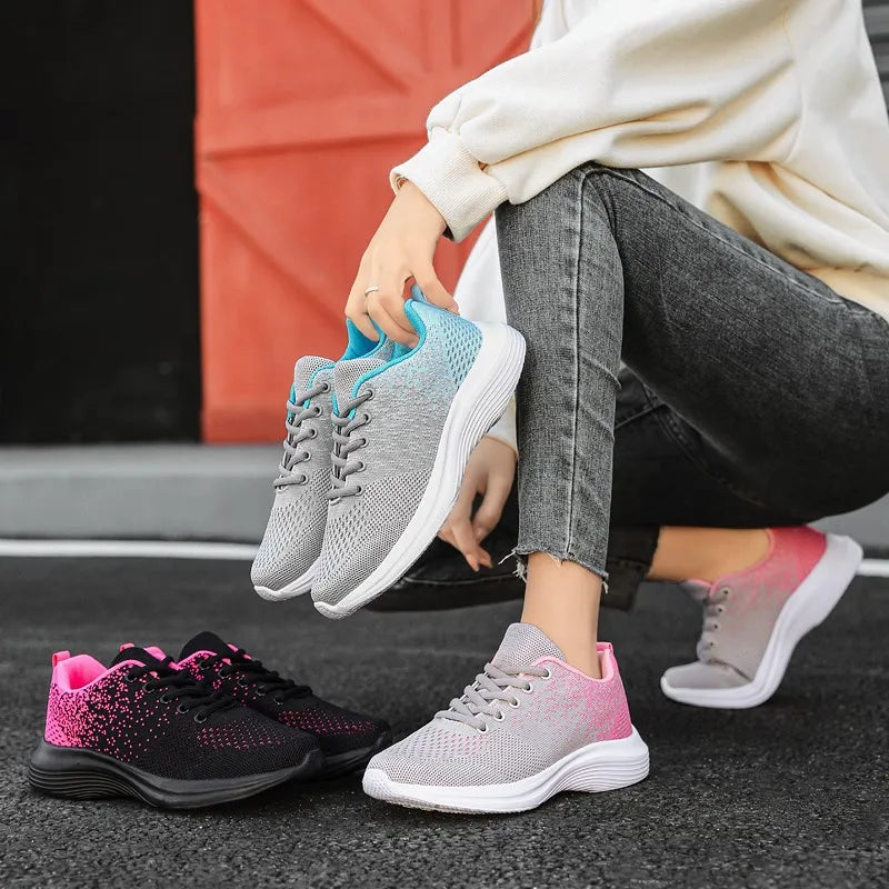 Breathable knit athletic trainers in light gray with blue accents and pink gradient detail.
