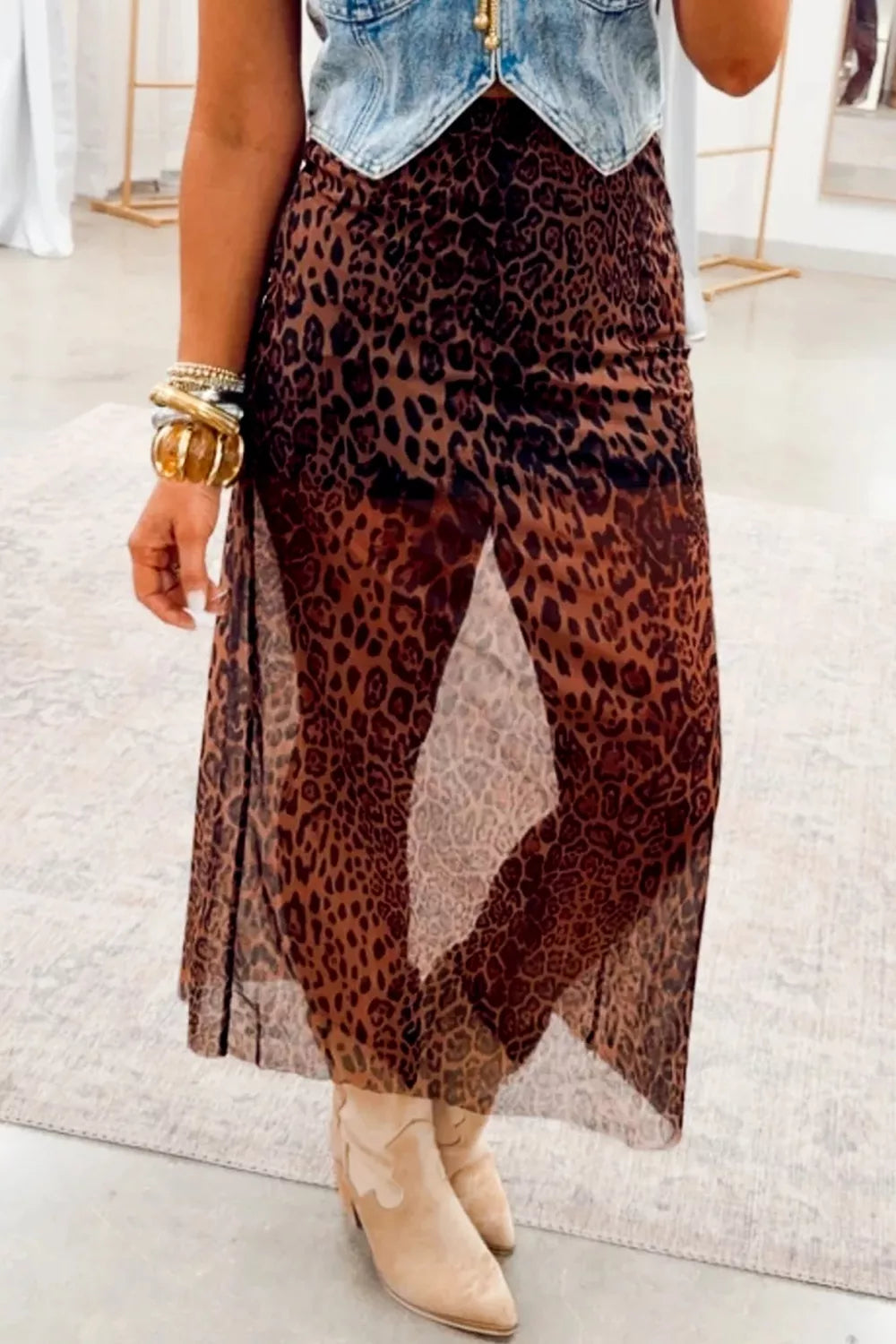 Sheer leopard print midi skirt with high slits, styled with a denim vest and boots.