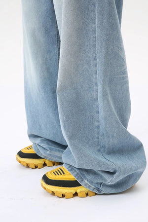 Oversized wash denim palazzo trousers in medium, styled with chunky yellow sneakers.