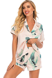Blush pink satin pajama set with botanical print, button-up top and shorts.