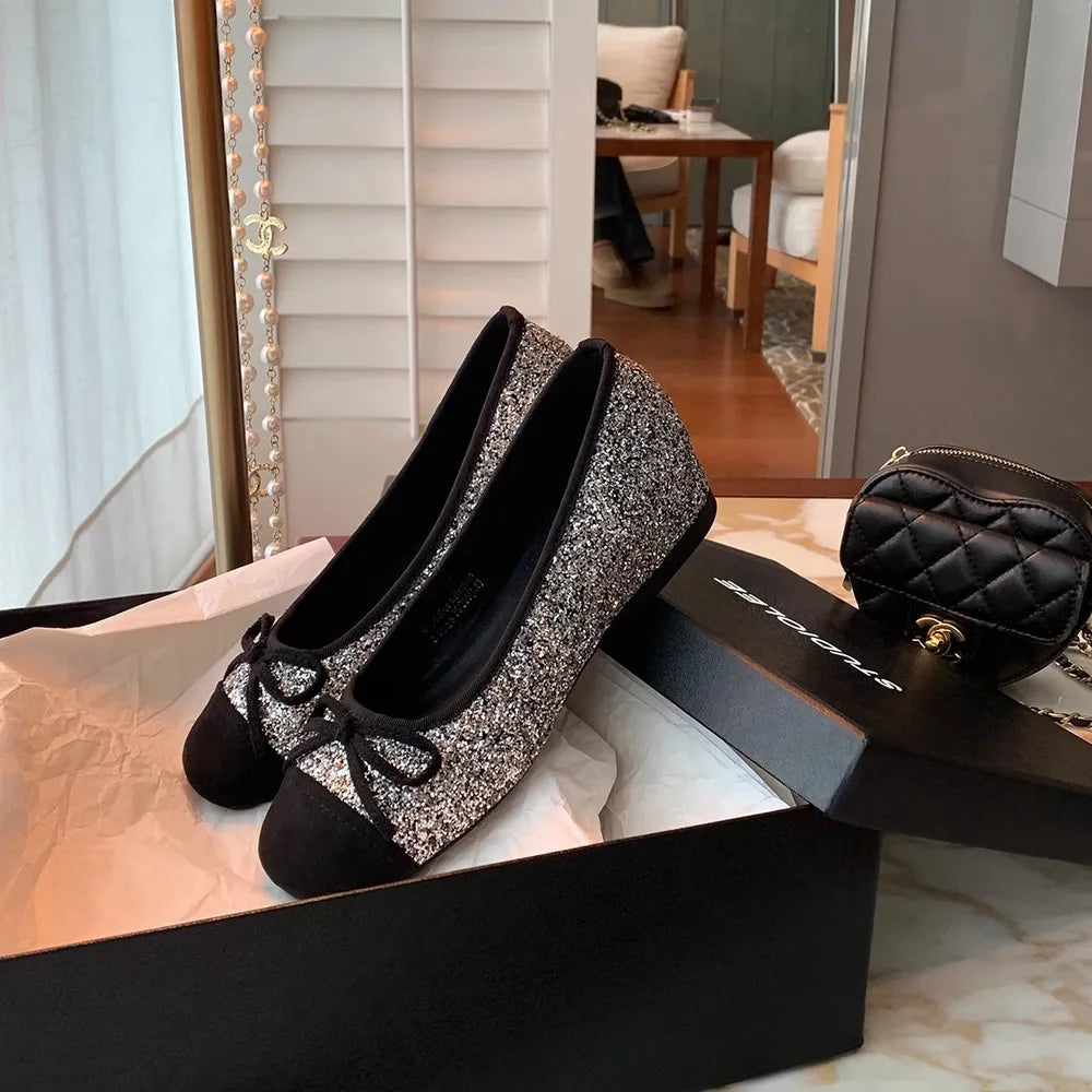 Glitter cap-toe ballet flats in black with a bow detail.