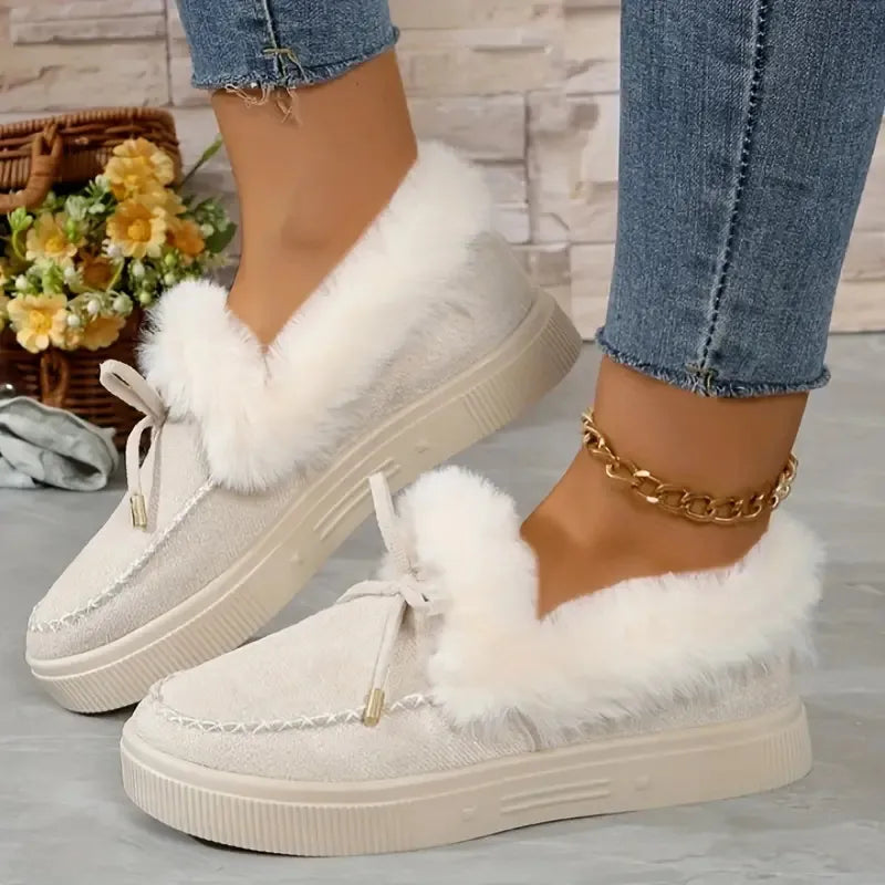 Beige suede loafers with fluffy shearling trim and bow detail.