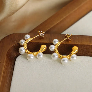 Sculpted gold hoop earrings with pearl accents, casual style.