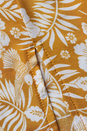 Bohemian floral print crop top and maxi skirt set in mustard yellow viscose with white tropical leaves and birds.