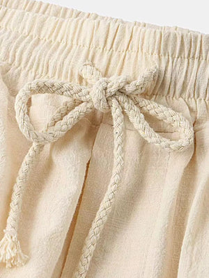Cream linen shorts with elastic waistband and braided drawstring tie.