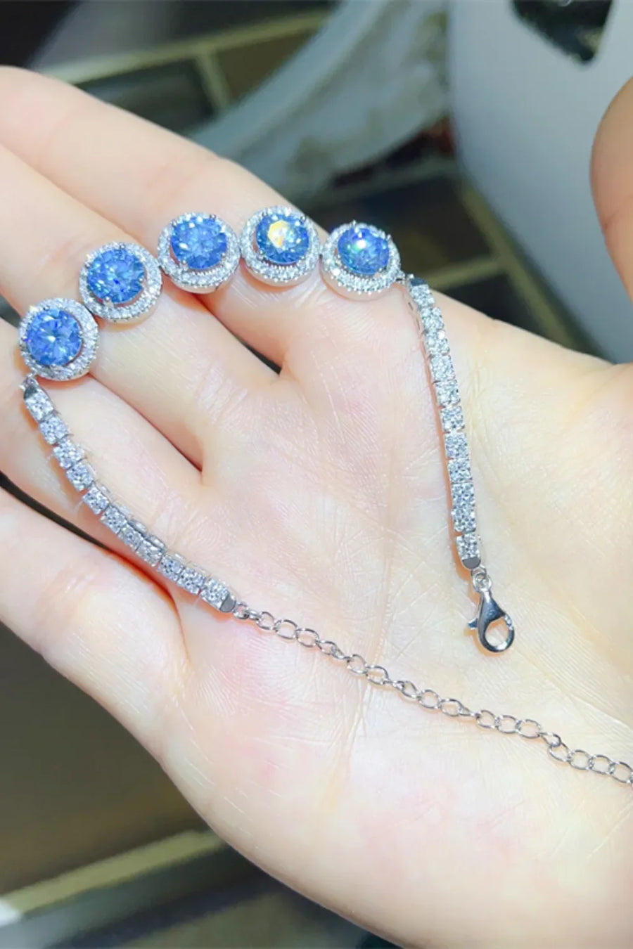 Blue moissanite and diamond halo bracelet in silver with a delicate chain and clasp.