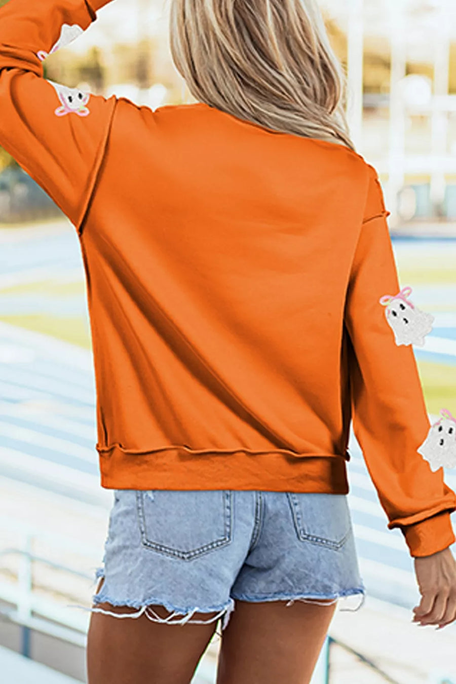 Orange sweatshirt featuring exposed seams and ghost