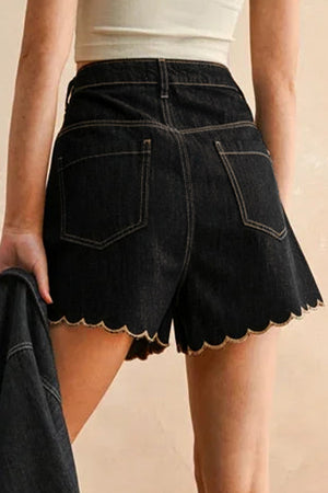 Black denim shorts with scalloped hem and contrast stitching.