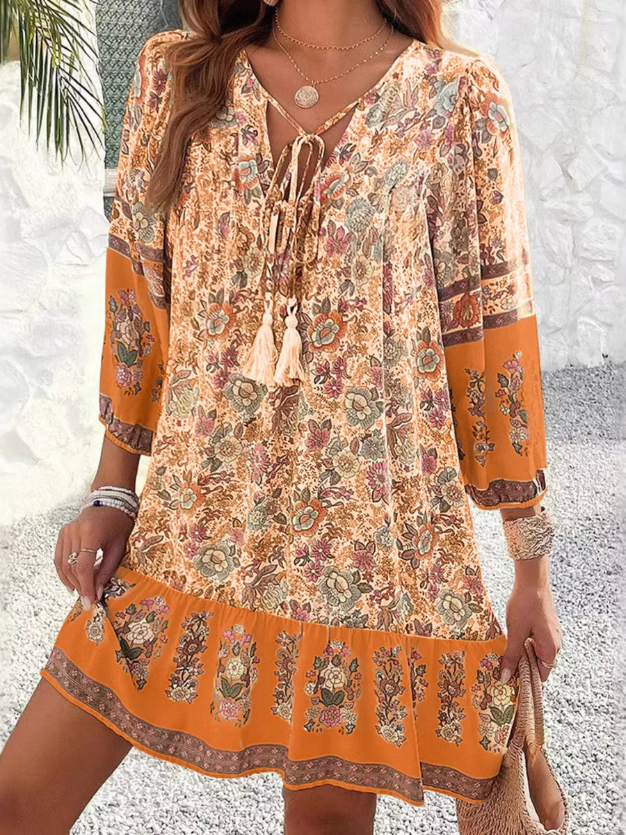 Vibrant floral tassel tie mini dress in ochre with peasant sleeves and tiered hem.