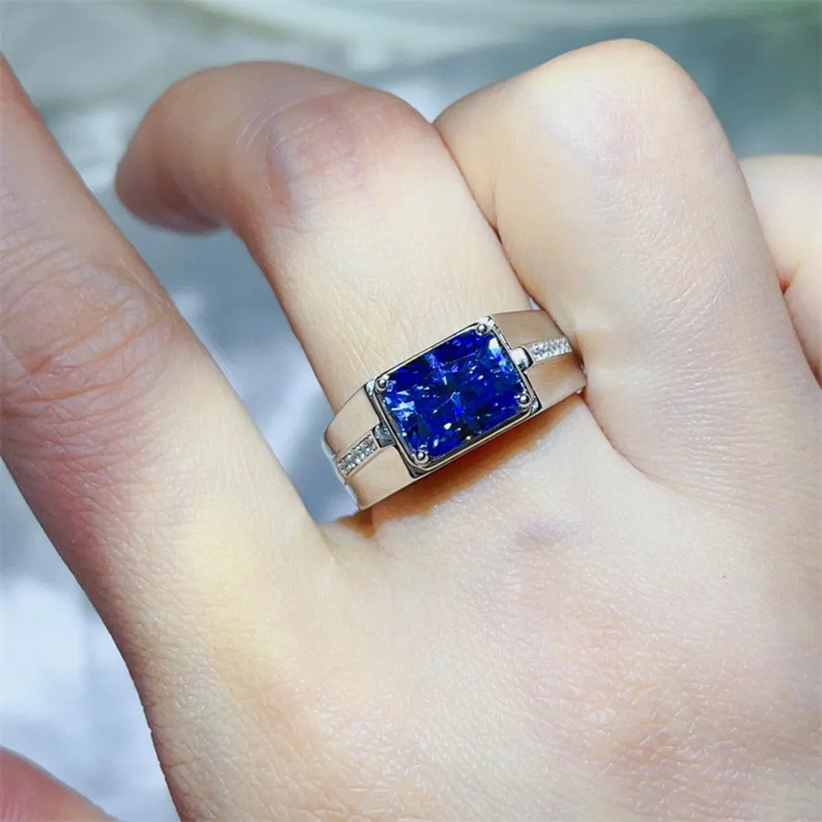 Blue emerald cut moissanite signet ring with diamond accents on band.
