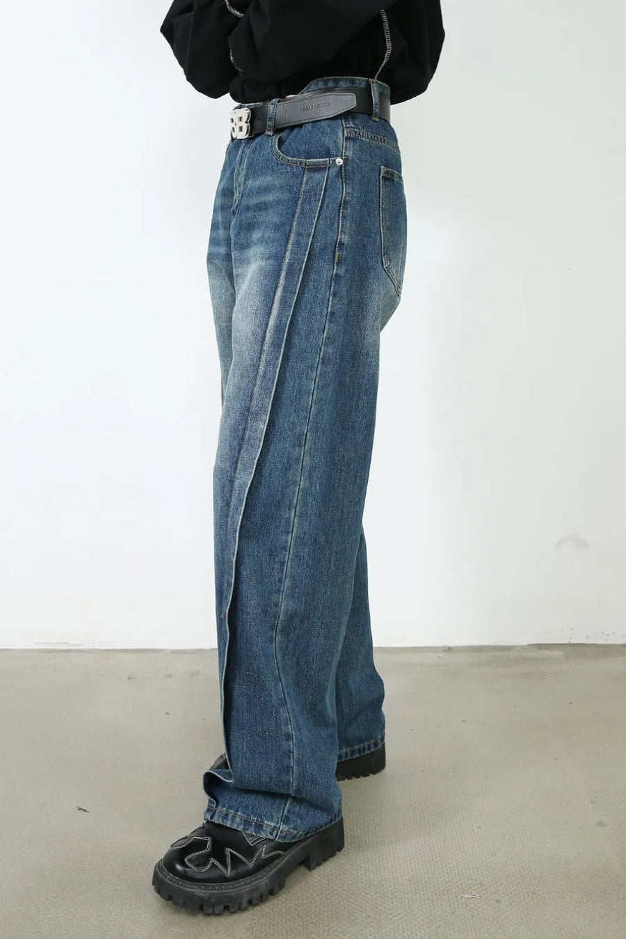 Medium wash denim jeans with wide legs and a prominent vertical seam detail.