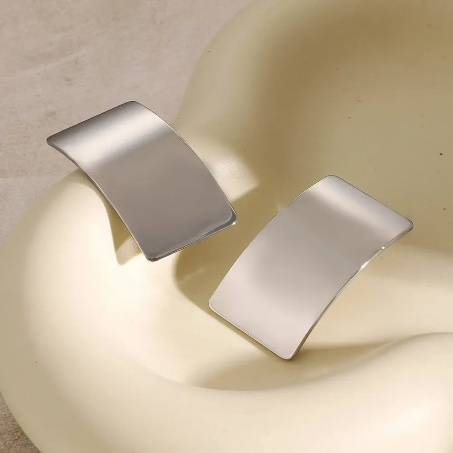 Sculpted silver-tone statement earrings with a bold, curved design.