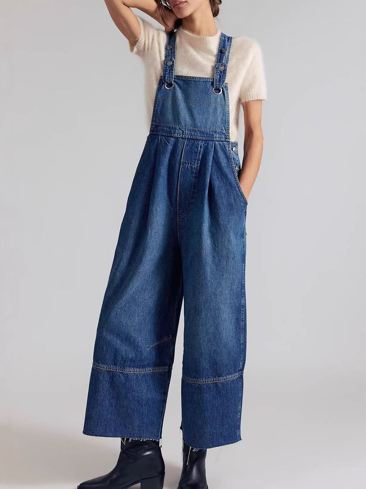 Light blue denim overalls with wide legs and raw hem, featuring adjustable straps and button details.
