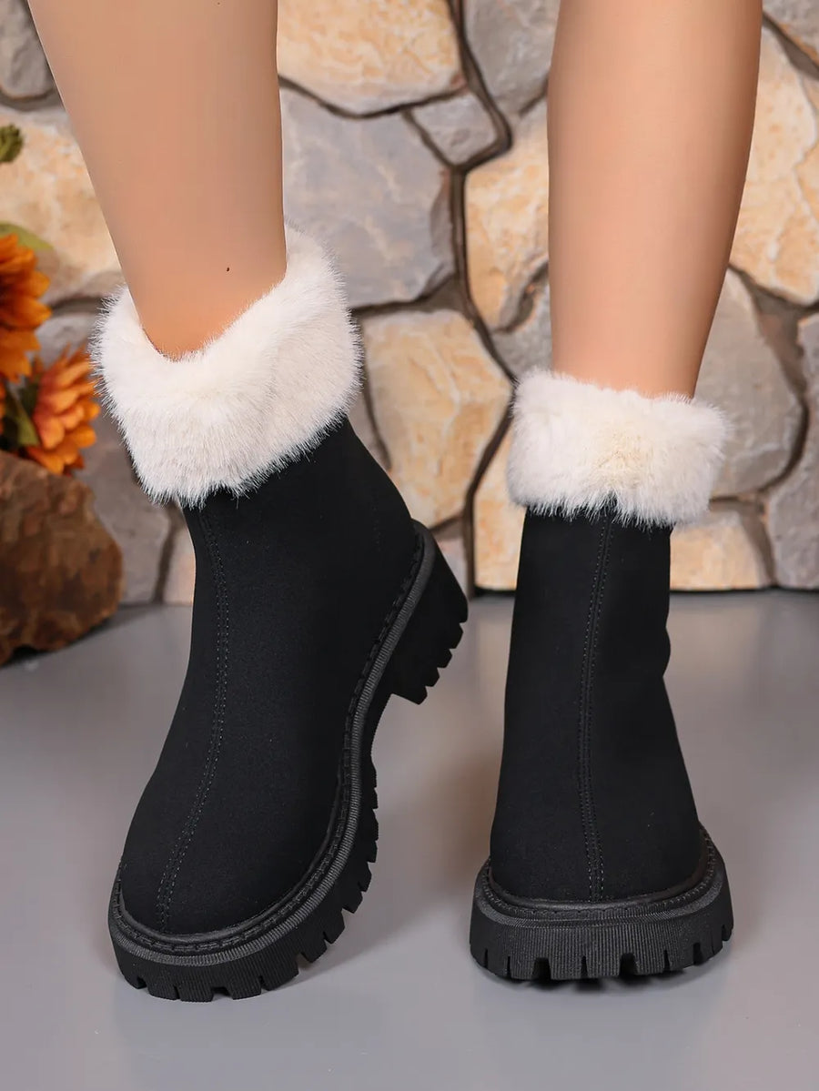 Black suede ankle boots with white faux fur trim and lug sole.