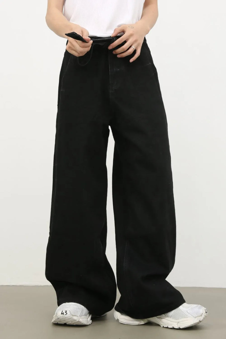Black denim jeans with exaggerated wide legs and a tie detail at the waist.