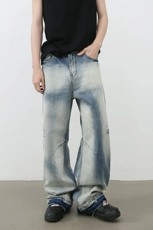 Distressed painterly wide-leg jeans in medium wash denim with paint splatters and artistic paneling.