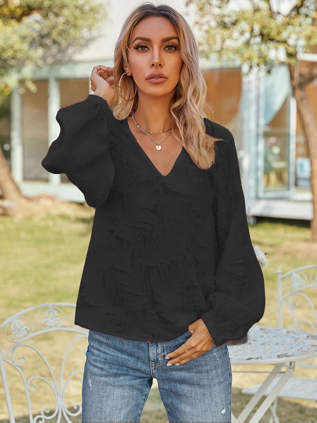 Black textured puff sleeve v-neck blouse with voluminous sleeves.