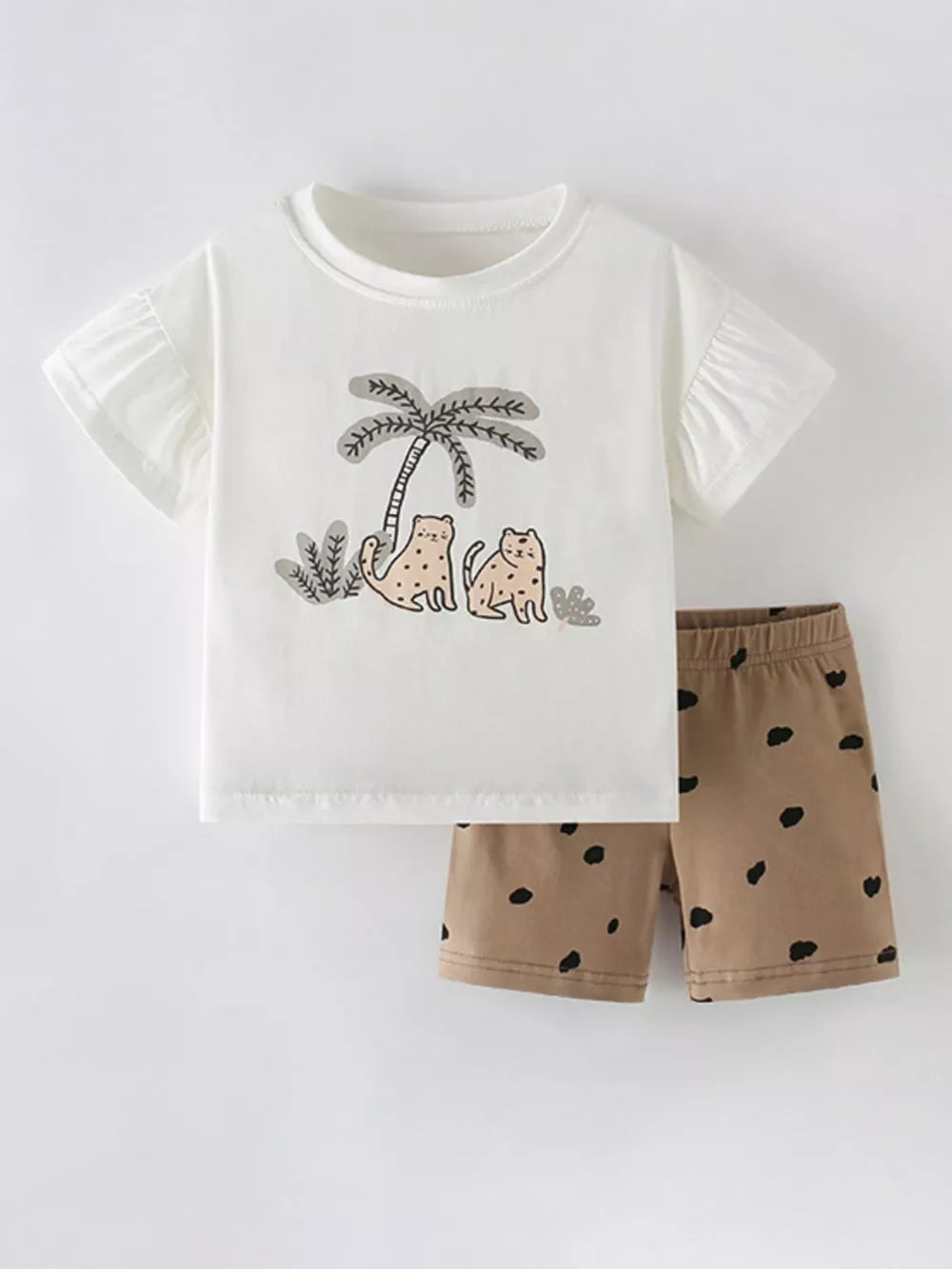 White cotton baby tee with ruffled sleeves and wildcat palm tree graphic, paired with brown shorts with black polka dots.